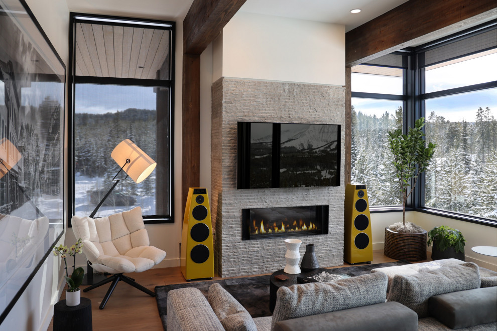 Example of a small trendy open concept light wood floor, brown floor and exposed beam living room design in Other with a music area, beige walls, a stacked stone fireplace and a wall-mounted tv