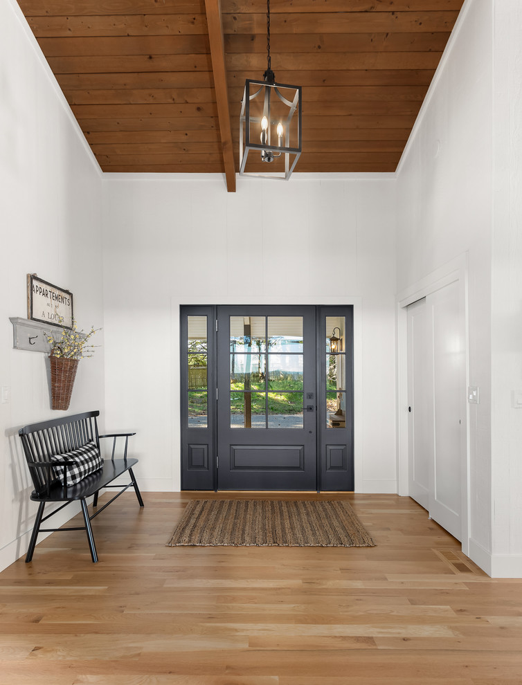 Inspiration for a mid-sized country foyer in Portland with white walls, light hardwood floors, a single front door, a blue front door and beige floor.