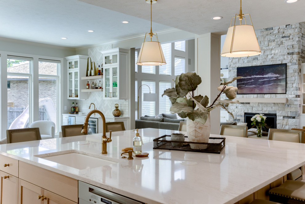 Example of a transitional light wood floor and beige floor open concept kitchen design with an undermount sink, white cabinets, quartzite countertops, multicolored backsplash, stainless steel appliances and an island