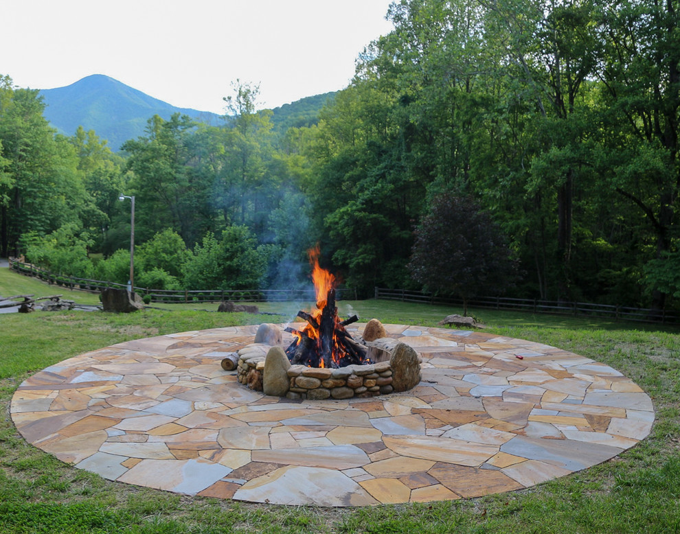 This is an example of a mid-sized country front yard patio in Other with a fire feature, natural stone pavers and no cover.