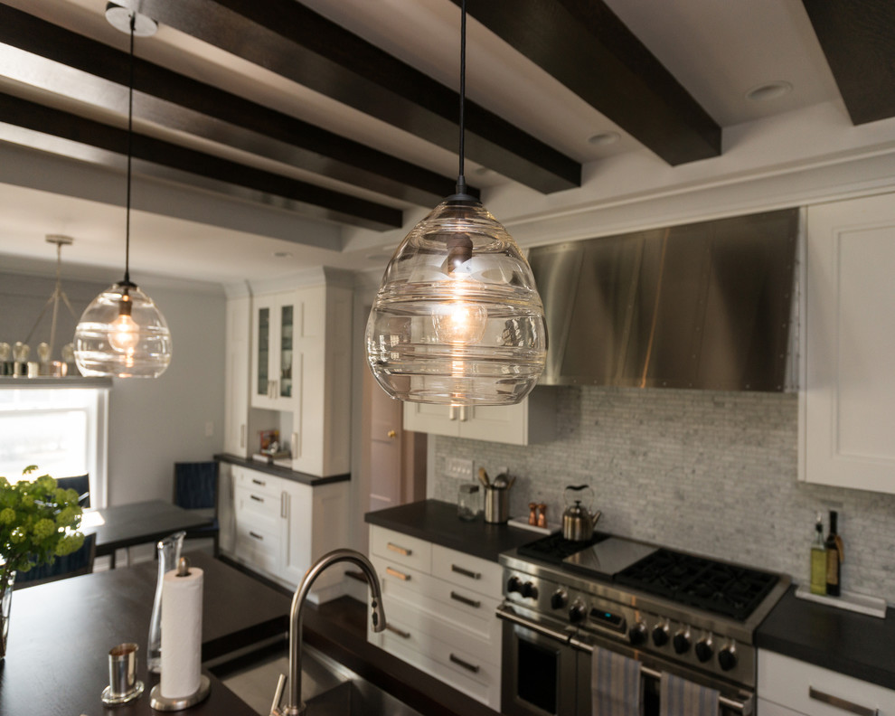 Example of a mid-sized transitional galley dark wood floor eat-in kitchen design in Boston with recessed-panel cabinets, white cabinets, wood countertops, gray backsplash, stainless steel appliances, an island, an undermount sink and stone tile backsplash