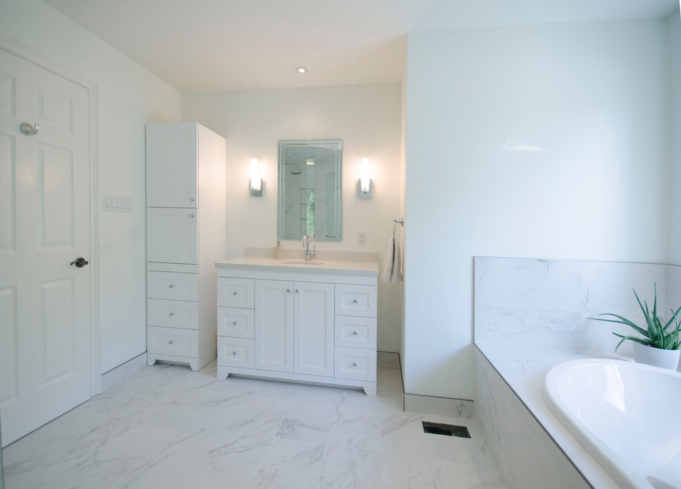 Mid-sized transitional master bathroom in Toronto with shaker cabinets, white cabinets, a drop-in tub, a corner shower, a two-piece toilet, white tile, porcelain tile, white walls, porcelain floors, an undermount sink, engineered quartz benchtops, white floor and a hinged shower door.