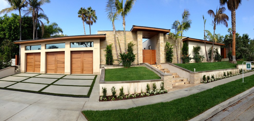 Inspiration for a mid-sized tropical split-level beige house exterior in Orange County with stone veneer and a flat roof.
