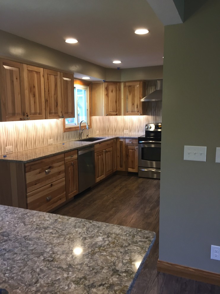 Example of a mid-sized mountain style u-shaped laminate floor and brown floor eat-in kitchen design in Omaha with an undermount sink, raised-panel cabinets, light wood cabinets, quartz countertops, beige backsplash, porcelain backsplash, stainless steel appliances, an island and gray countertops