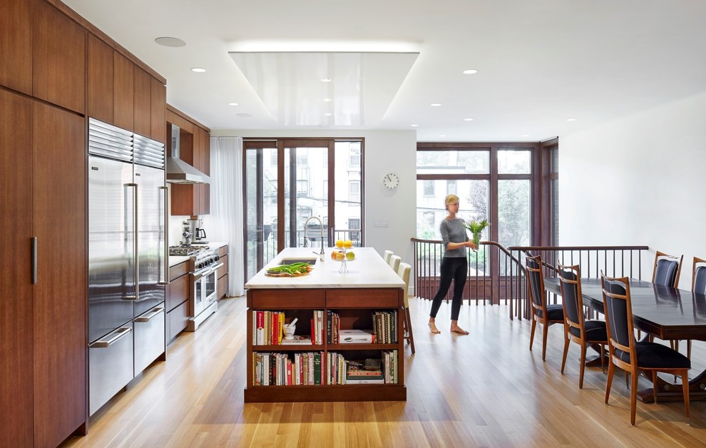 Contemporary eat-in kitchen in New York with an undermount sink, flat-panel cabinets, medium wood cabinets, stainless steel appliances, light hardwood floors and with island.