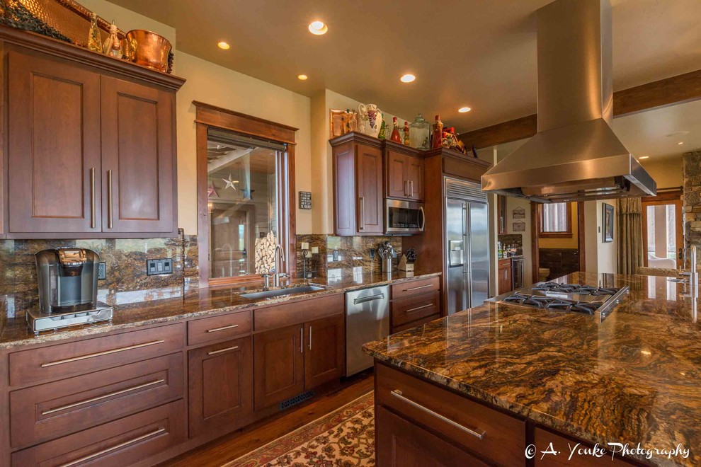 Example of a mid-sized mountain style l-shaped dark wood floor open concept kitchen design with an undermount sink, shaker cabinets, dark wood cabinets, granite countertops, multicolored backsplash, stone slab backsplash, stainless steel appliances and an island