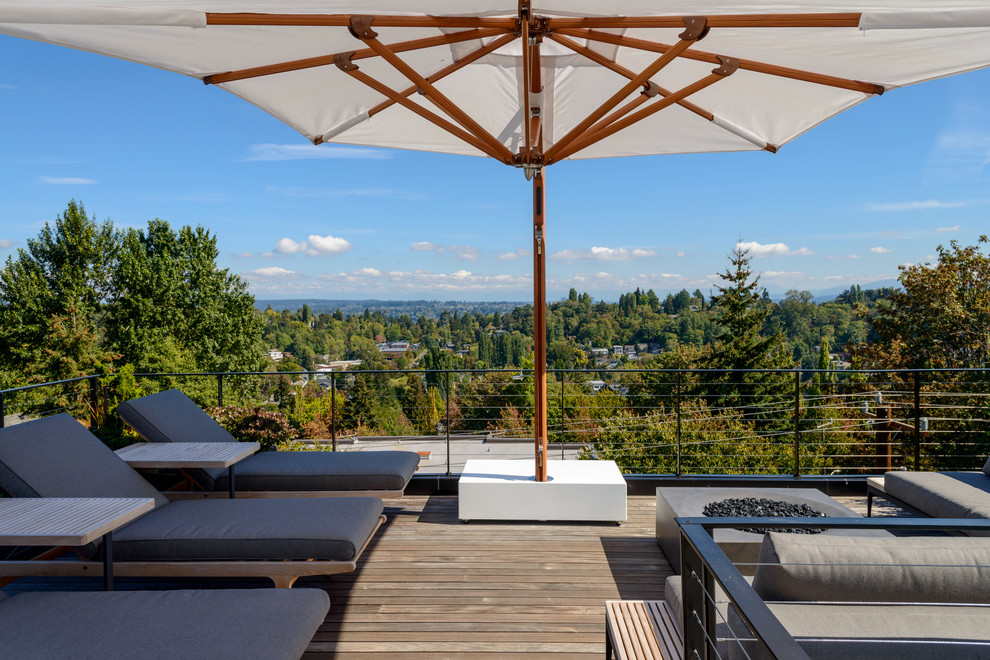 This is an example of a mid-sized modern rooftop deck in Seattle with with fireplace and an awning.