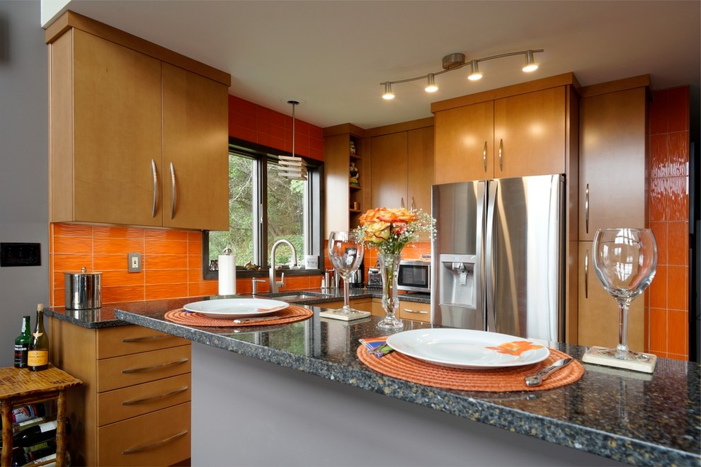 This is an example of a small contemporary l-shaped separate kitchen in Philadelphia with an undermount sink, flat-panel cabinets, light wood cabinets, quartz benchtops, orange splashback, glass tile splashback, stainless steel appliances, laminate floors, no island, brown floor and blue benchtop.