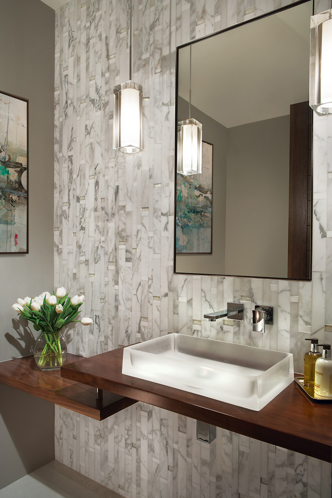 This is an example of a small contemporary powder room in Phoenix with grey walls, a vessel sink, wood benchtops, open cabinets, a one-piece toilet, beige tile, marble, marble floors, white floor and brown benchtops.