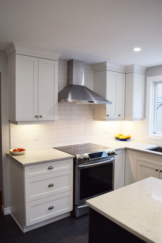 Inspiration for a mid-sized transitional l-shaped ceramic tile enclosed kitchen remodel in Ottawa with an undermount sink, shaker cabinets, white cabinets, quartz countertops, white backsplash, subway tile backsplash, stainless steel appliances and an island