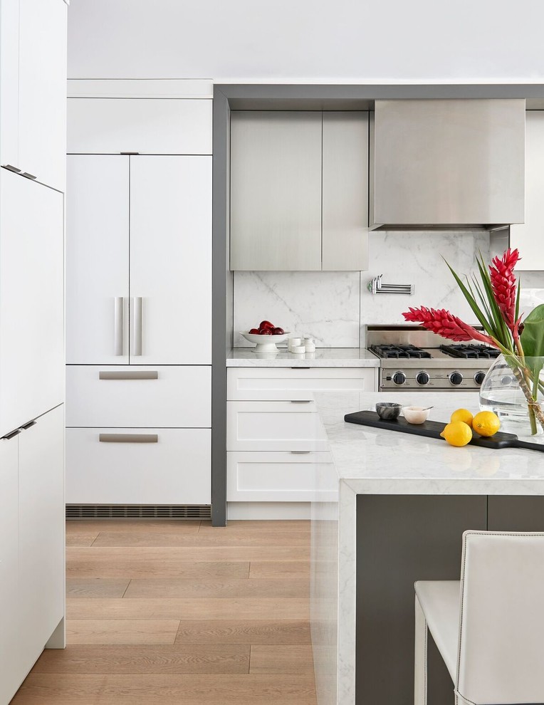 Inspiration for a mid-sized modern l-shaped open plan kitchen in Toronto with an undermount sink, flat-panel cabinets, white cabinets, marble benchtops, white splashback, stainless steel appliances, light hardwood floors, with island, marble splashback and beige floor.