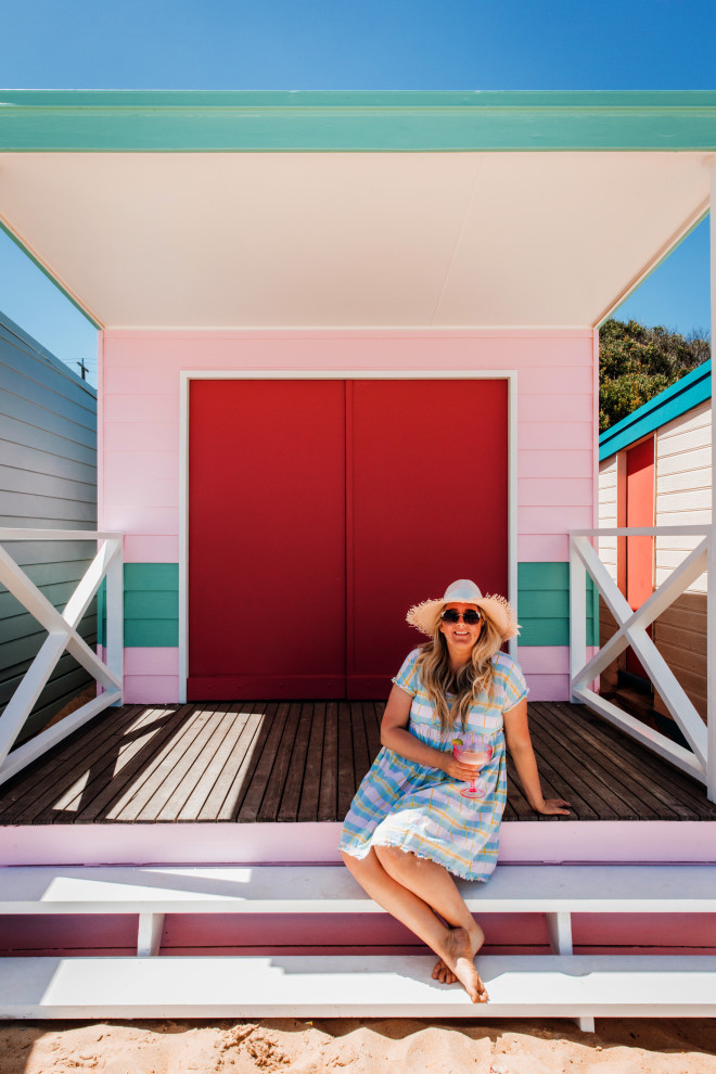 Photo of a small beach style one-storey pink exterior with wood siding.
