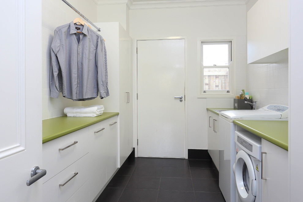 This is an example of a mid-sized contemporary galley dedicated laundry room in Brisbane with flat-panel cabinets, white cabinets, white walls, a drop-in sink, ceramic floors, green benchtop and laminate benchtops.