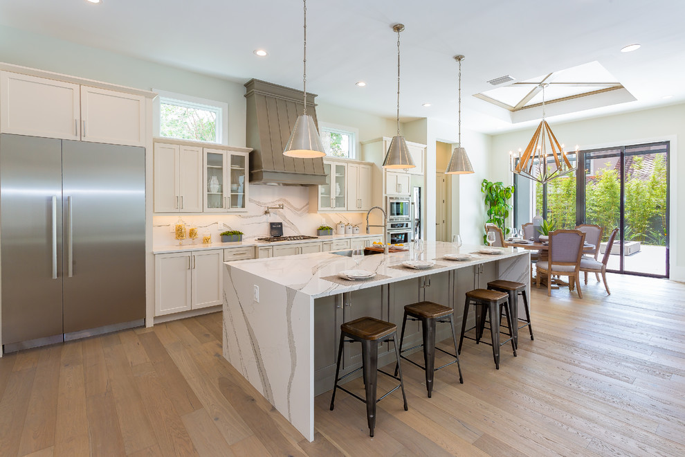 Inspiration for a transitional eat-in kitchen in Orlando with an undermount sink, shaker cabinets, white cabinets, marble benchtops, white splashback, marble splashback, stainless steel appliances, light hardwood floors, with island, beige floor and white benchtop.