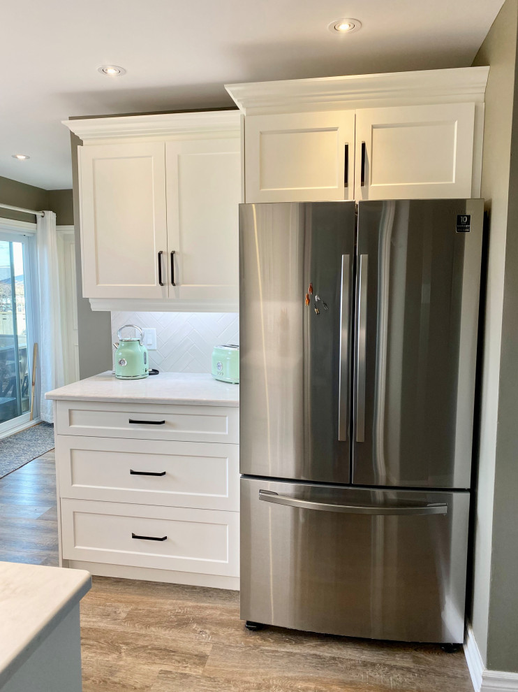 Example of a mid-sized transitional l-shaped enclosed kitchen design with a double-bowl sink, recessed-panel cabinets, white cabinets, gray backsplash, glass tile backsplash and no island