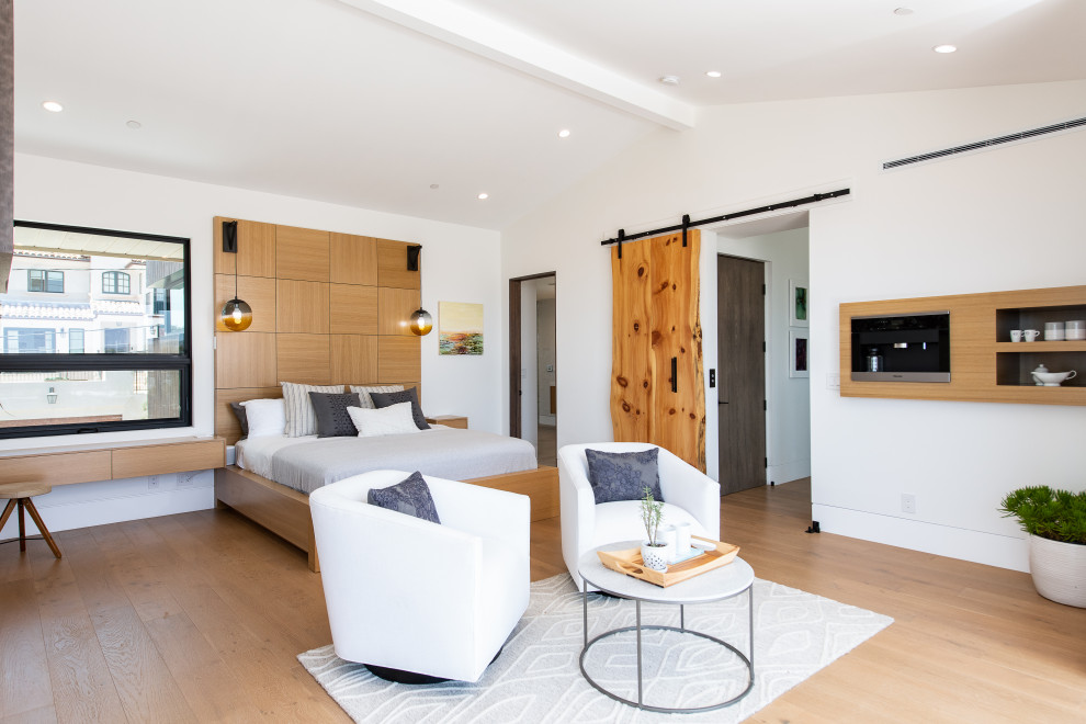 Geräumiges Modernes Hauptschlafzimmer mit weißer Wandfarbe, braunem Holzboden, braunem Boden und gewölbter Decke in Orange County
