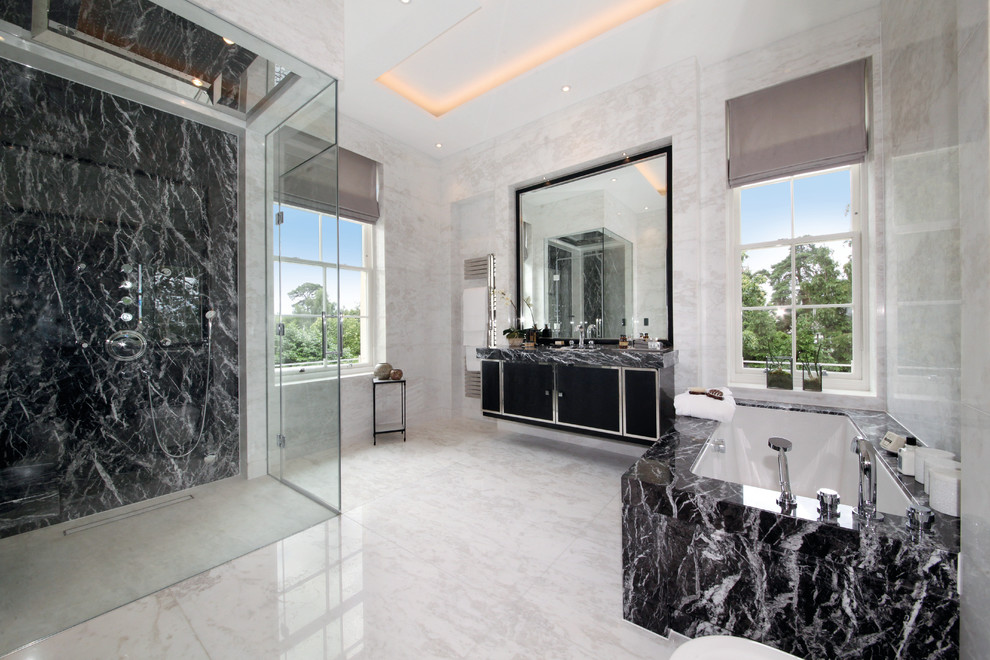 Inspiration for a contemporary master bathroom in Surrey with flat-panel cabinets, black cabinets, a curbless shower, marble benchtops, an undermount tub, beige walls and a hinged shower door.