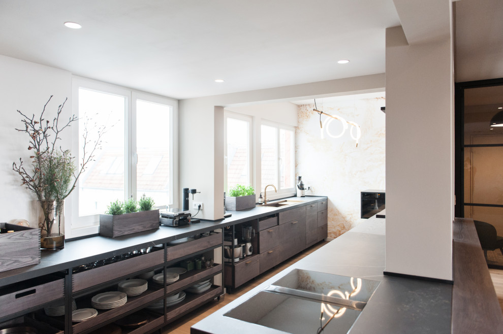 Design ideas for a large contemporary galley open plan kitchen in Berlin with beaded cabinets, a built-in sink, grey cabinets, wood worktops, white splashback, brown floors and grey worktops.