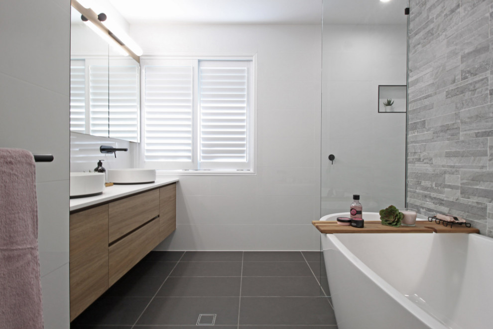 Design ideas for a mid-sized modern kids bathroom in Brisbane with shaker cabinets, light wood cabinets, a freestanding tub, an alcove shower, a two-piece toilet, white tile, ceramic tile, white walls, porcelain floors, a vessel sink, engineered quartz benchtops, grey floor, an open shower and white benchtops.