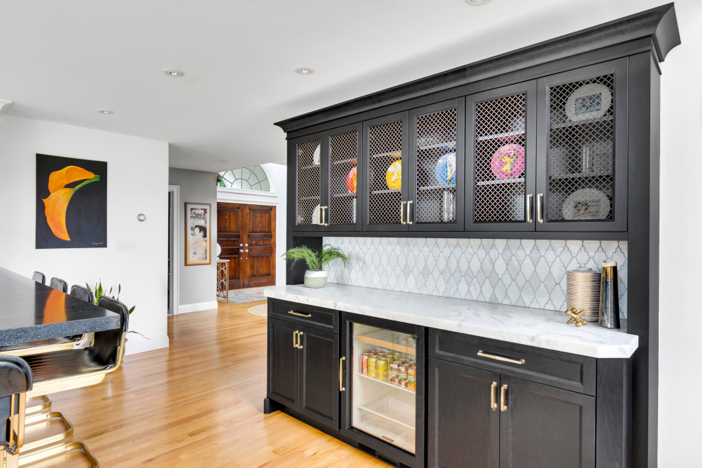 Design ideas for a large classic l-shaped home bar in New York with a submerged sink, shaker cabinets, black cabinets, engineered stone countertops, white splashback, marble splashback, light hardwood flooring, beige floors and white worktops.