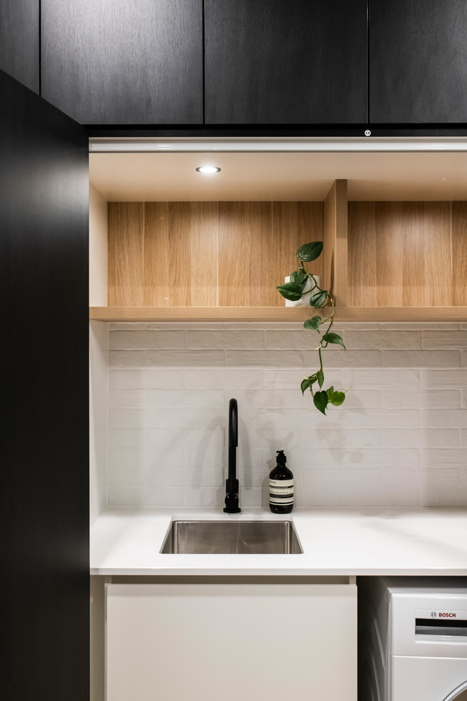 Large contemporary galley utility room in Melbourne with porcelain floors, brown floor, a drop-in sink, open cabinets, light wood cabinets, laminate benchtops, white walls, an integrated washer and dryer and white benchtop.