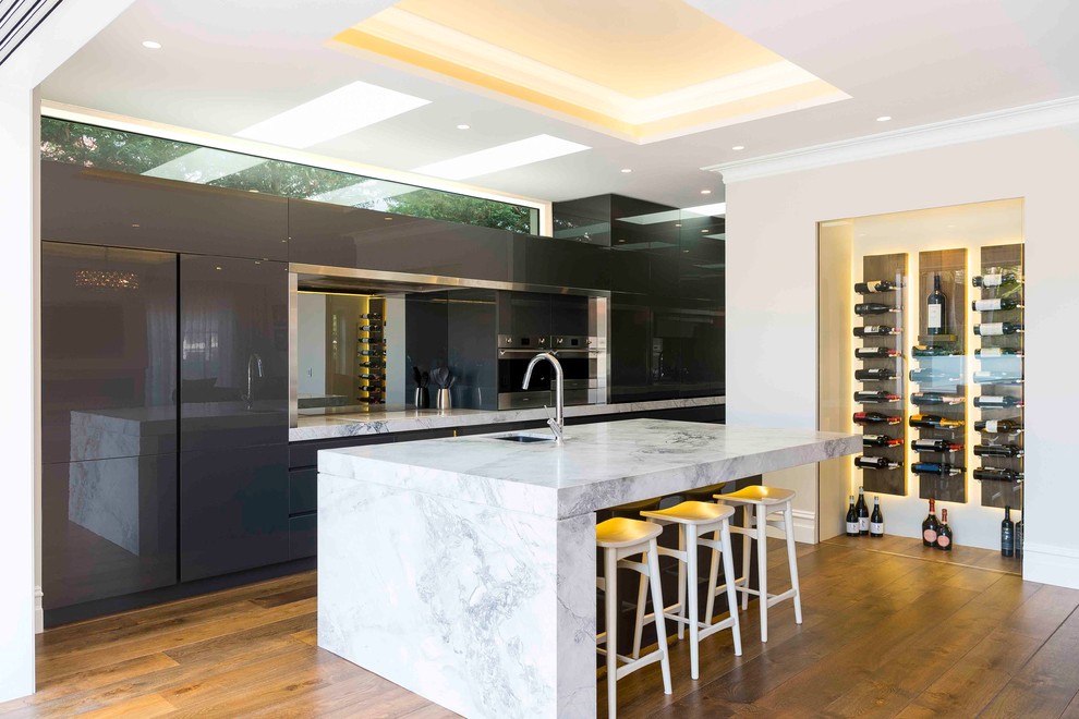 Design ideas for a contemporary kitchen in Sydney with an undermount sink, flat-panel cabinets, grey cabinets, mirror splashback, stainless steel appliances, medium hardwood floors, with island and white benchtop.