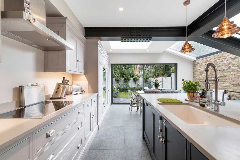Inspiration for a mid-sized contemporary single-wall open plan kitchen in London with an integrated sink, shaker cabinets, grey cabinets, concrete benchtops, white splashback, stainless steel appliances, concrete floors, with island and grey floor.
