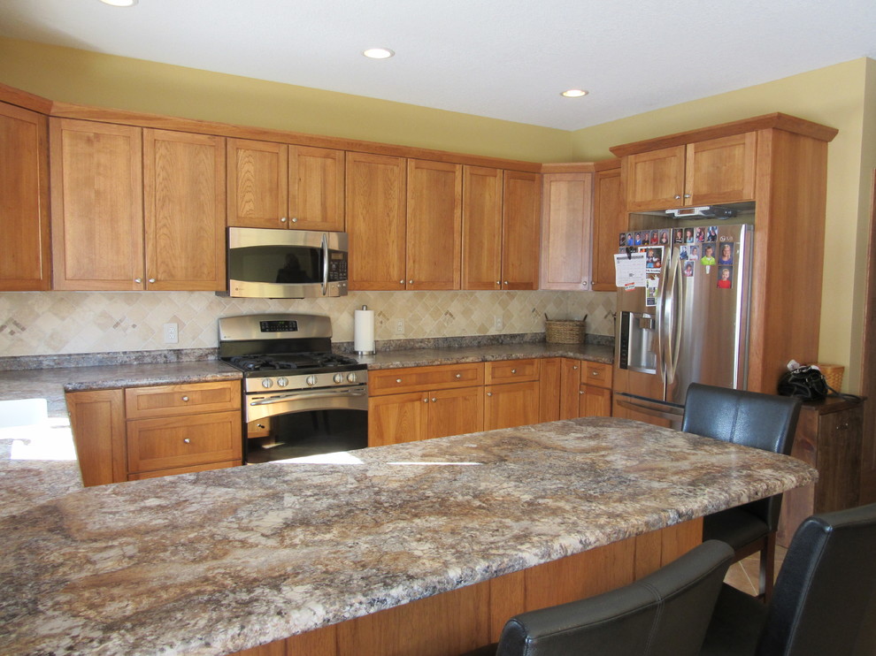 Example of a transitional u-shaped ceramic tile eat-in kitchen design with an integrated sink, shaker cabinets, medium tone wood cabinets, laminate countertops, beige backsplash, stone tile backsplash, stainless steel appliances and a peninsula
