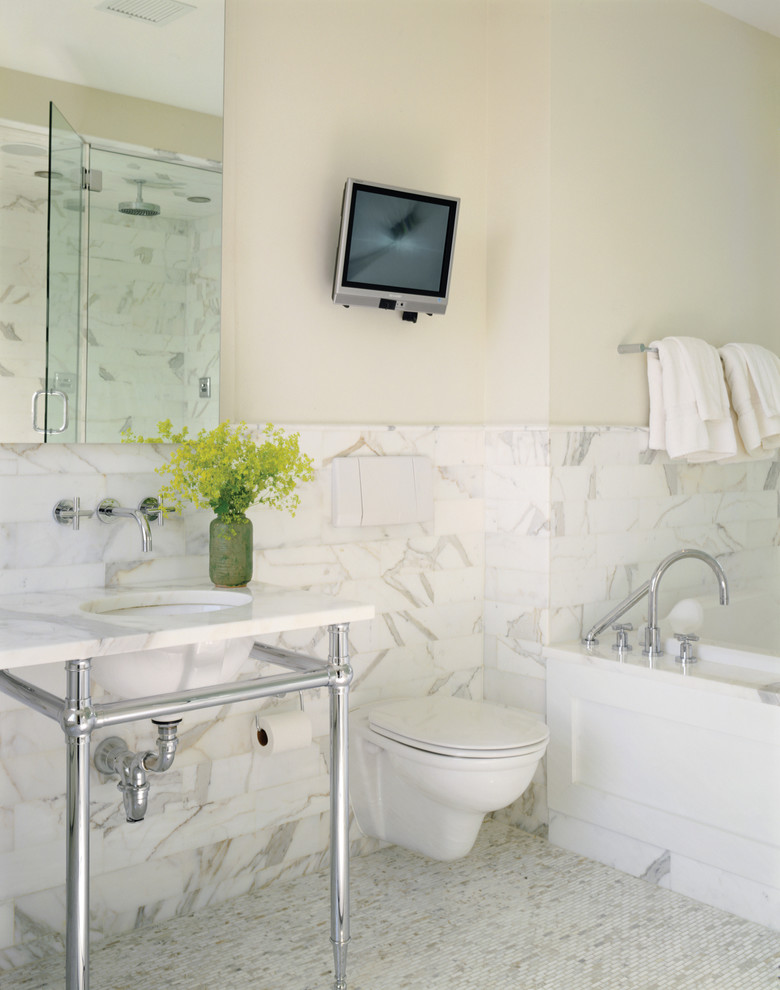 Photo of a contemporary bathroom in New York with a wall-mount toilet, a console sink and marble.