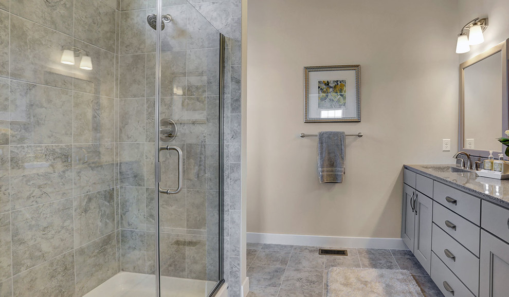 Inspiration for a mid-sized traditional master bathroom in Other with grey cabinets, an alcove shower, beige walls, ceramic floors, an integrated sink, engineered quartz benchtops, grey floor and a hinged shower door.