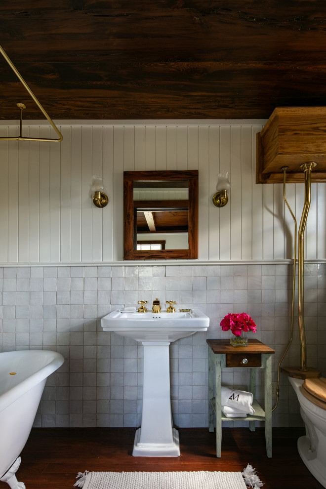 Inspiration för mellanstora lantliga en-suite badrum, med ett badkar med tassar, en dusch/badkar-kombination, vit kakel, keramikplattor, mörkt trägolv, ett piedestal handfat och dusch med duschdraperi