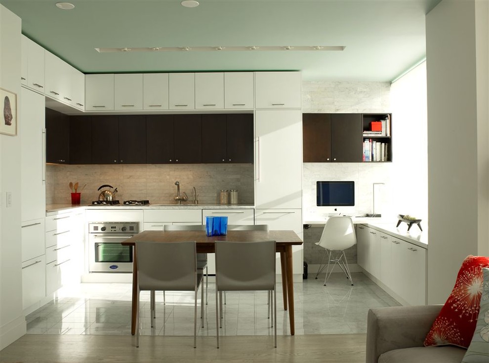 This is an example of a modern l-shaped open plan kitchen in New York with stainless steel appliances, flat-panel cabinets, white cabinets, white splashback and stone tile splashback.