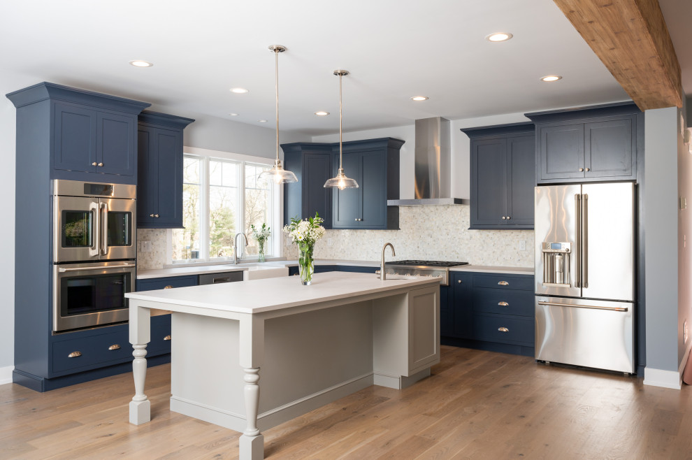 This is an example of a traditional kitchen in Philadelphia with shaker cabinets, blue cabinets, with island, brown floor and white benchtop.