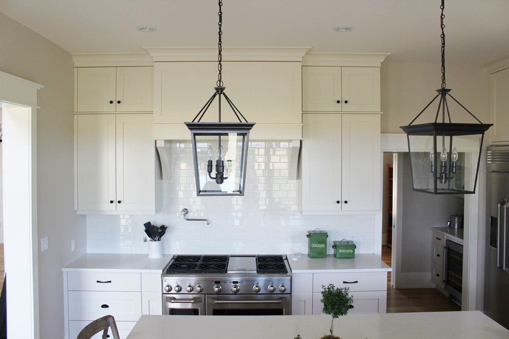 Eat-in kitchen - large transitional l-shaped eat-in kitchen idea in Toronto with an undermount sink, shaker cabinets, white cabinets, quartz countertops, white backsplash, stainless steel appliances and an island