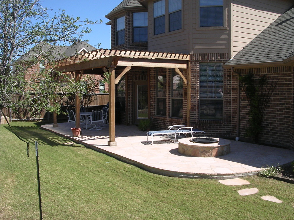 This is an example of a mid-sized traditional backyard patio in Dallas with an outdoor kitchen, natural stone pavers and a pergola.