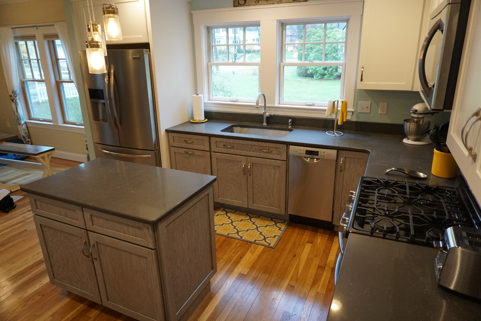 Mid-sized transitional u-shaped medium tone wood floor eat-in kitchen photo in Boston with an undermount sink, shaker cabinets, gray cabinets, quartz countertops, black backsplash, stainless steel appliances and an island