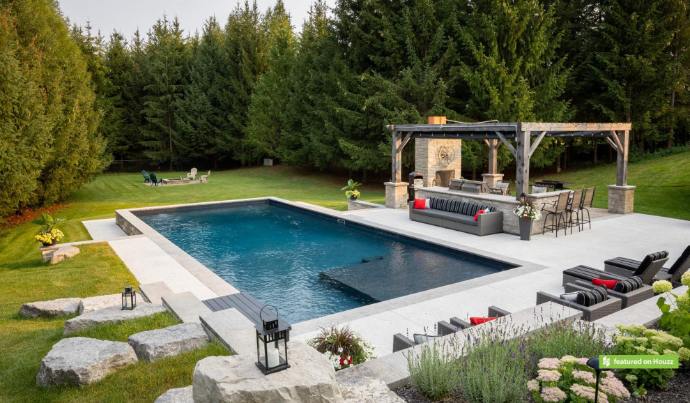 Foto de piscina rústica grande rectangular en patio trasero con suelo de hormigón estampado y paisajismo de piscina