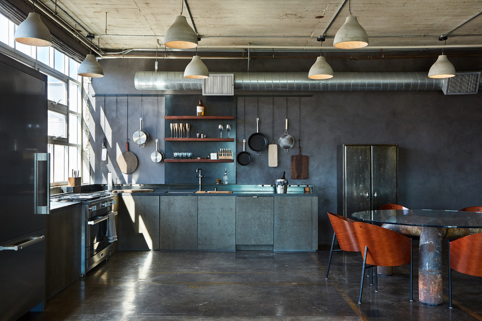 Example of a mid-sized urban l-shaped concrete floor and brown floor open concept kitchen design in Los Angeles with flat-panel cabinets, gray cabinets, granite countertops, gray backsplash, no island, black countertops, an undermount sink and stainless steel appliances