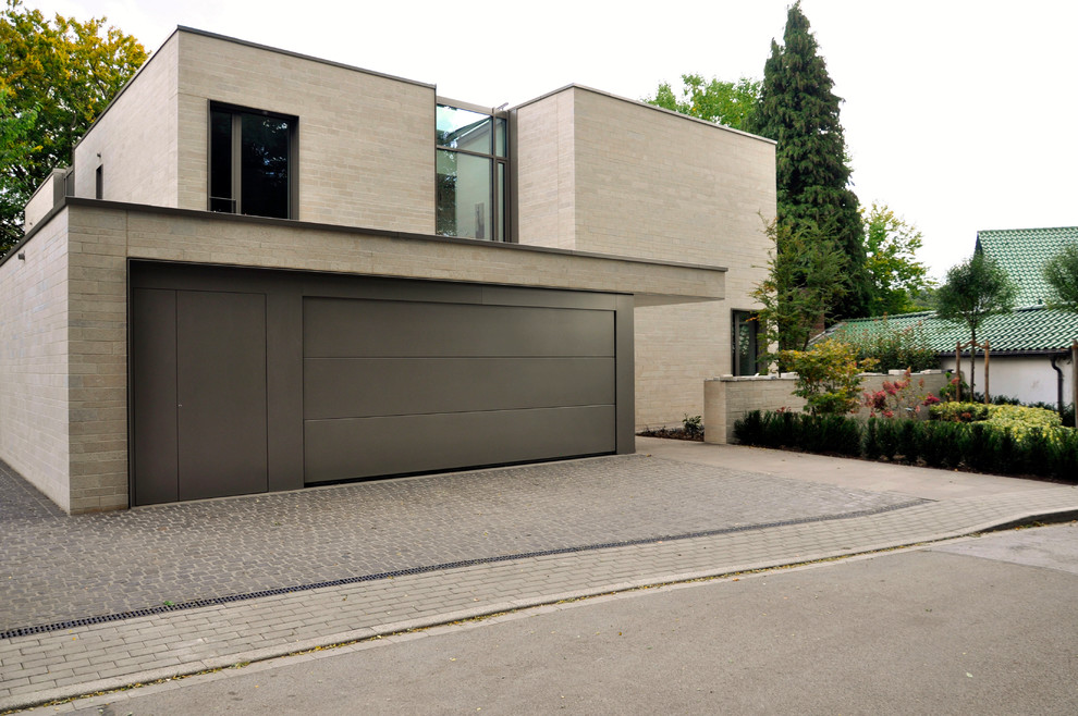 Design ideas for a large contemporary two-storey beige exterior in Essen with stone veneer and a flat roof.