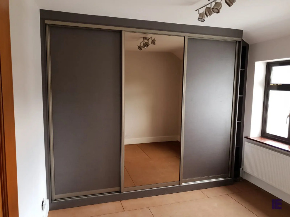 Aménagement d'une petite armoire encastrée contemporaine avec un placard à porte plane, des portes de placard marrons, un sol en contreplaqué et un sol marron.