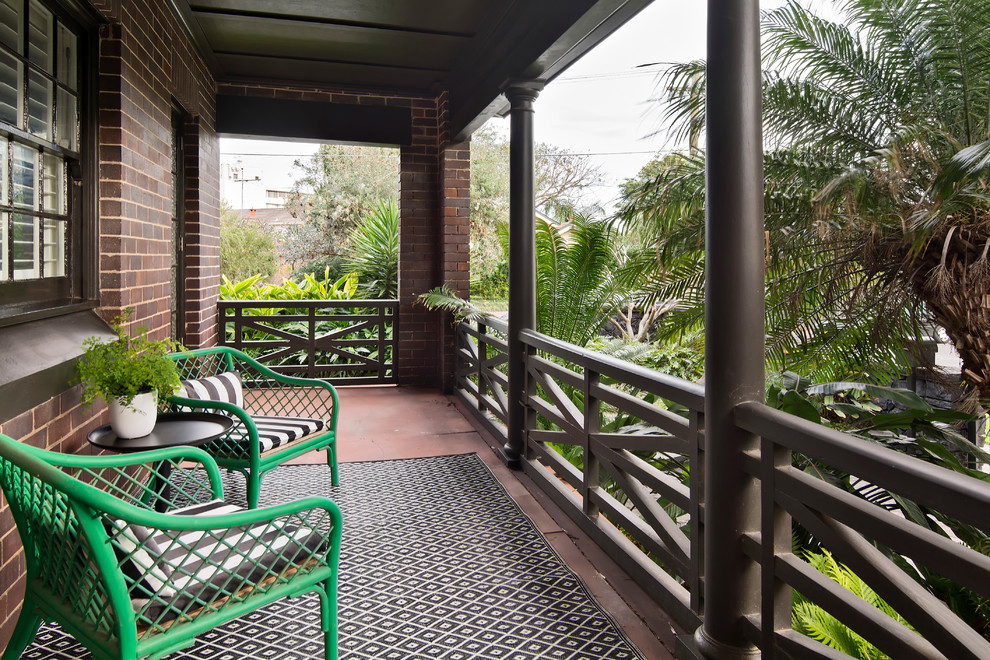 This is an example of a small tropical balcony in Sydney with an awning and wood railing.