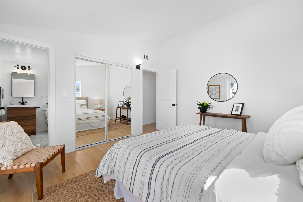 Imagen de dormitorio principal y abovedado retro de tamaño medio con paredes blancas y suelo laminado