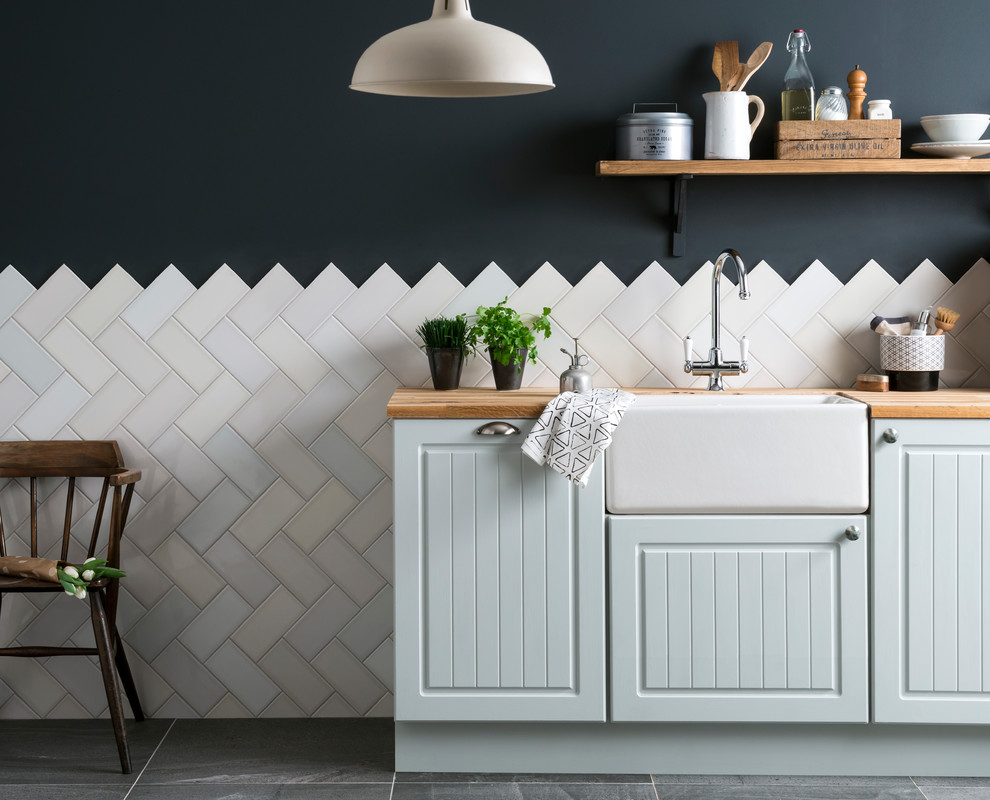 Inspiration for a mid-sized contemporary kitchen in Other with a farmhouse sink, blue cabinets, wood benchtops, white splashback, ceramic splashback, ceramic floors and black floor.