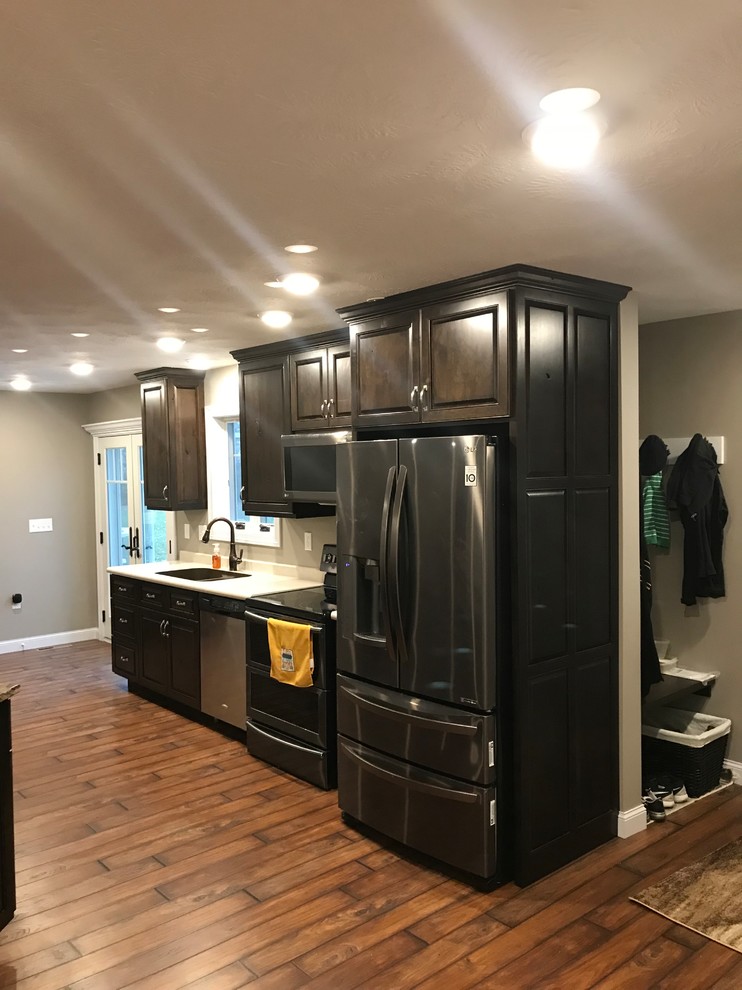 Inspiration for a large timeless galley dark wood floor and brown floor open concept kitchen remodel with raised-panel cabinets, laminate countertops, stainless steel appliances, an undermount sink, dark wood cabinets and an island