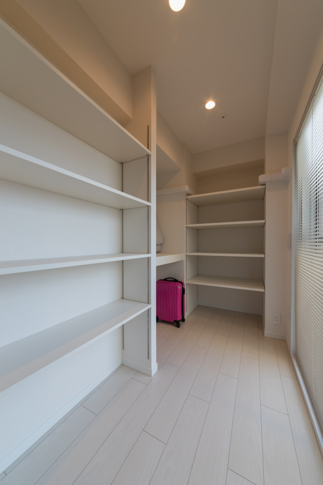 Coastal gender neutral walk-in wardrobe in Other with plywood flooring and white floors.