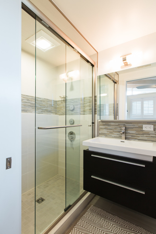 Inspiration for a small contemporary master bathroom in San Francisco with an integrated sink, flat-panel cabinets, black cabinets, solid surface benchtops, an alcove shower, a two-piece toilet, gray tile, glass tile, white walls and porcelain floors.