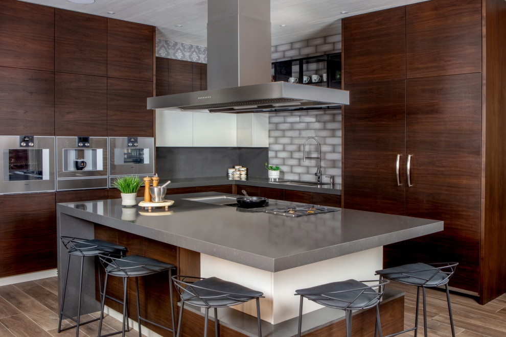 Photo of a mid-sized modern l-shaped eat-in kitchen in Toronto with an undermount sink, flat-panel cabinets, dark wood cabinets, quartz benchtops, grey splashback, subway tile splashback, stainless steel appliances, medium hardwood floors, with island, beige floor and grey benchtop.