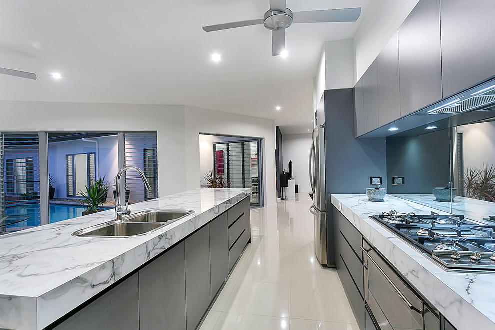 Photo of a mid-sized modern galley eat-in kitchen in Cairns with a drop-in sink, laminate benchtops, metallic splashback, mirror splashback, stainless steel appliances, porcelain floors and with island.