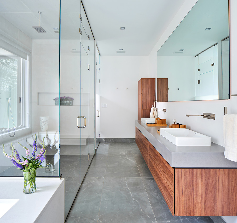 Inspiration for a contemporary master gray floor walk-in shower remodel in New York with flat-panel cabinets, medium tone wood cabinets, white walls, a vessel sink, concrete countertops, a hinged shower door and gray countertops