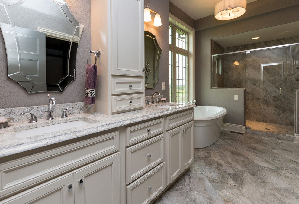 Inspiration for a transitional master beige tile freestanding bathtub remodel with a vessel sink, white cabinets, quartz countertops, a two-piece toilet and gray walls